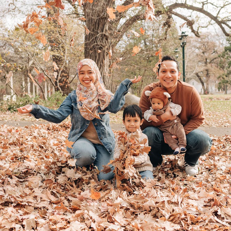 Smiling family throws leaves for their free outdoor fall photoshoot
