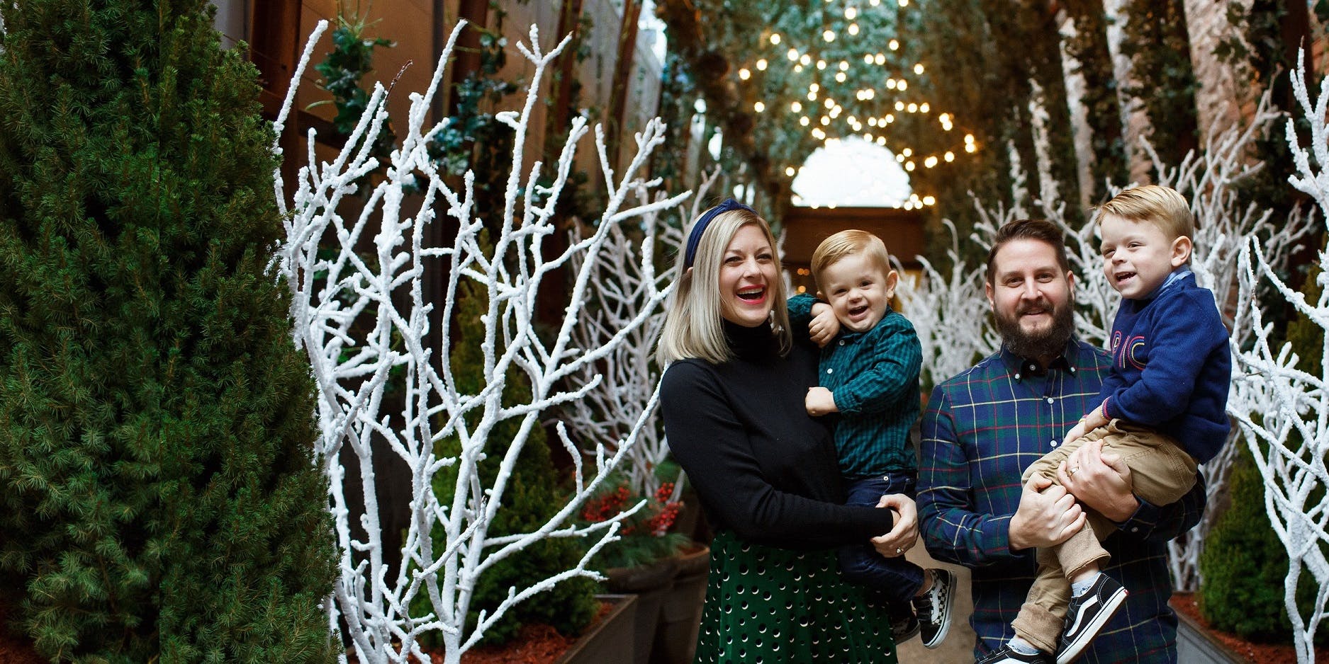 family with two kids standing under christmas decorations