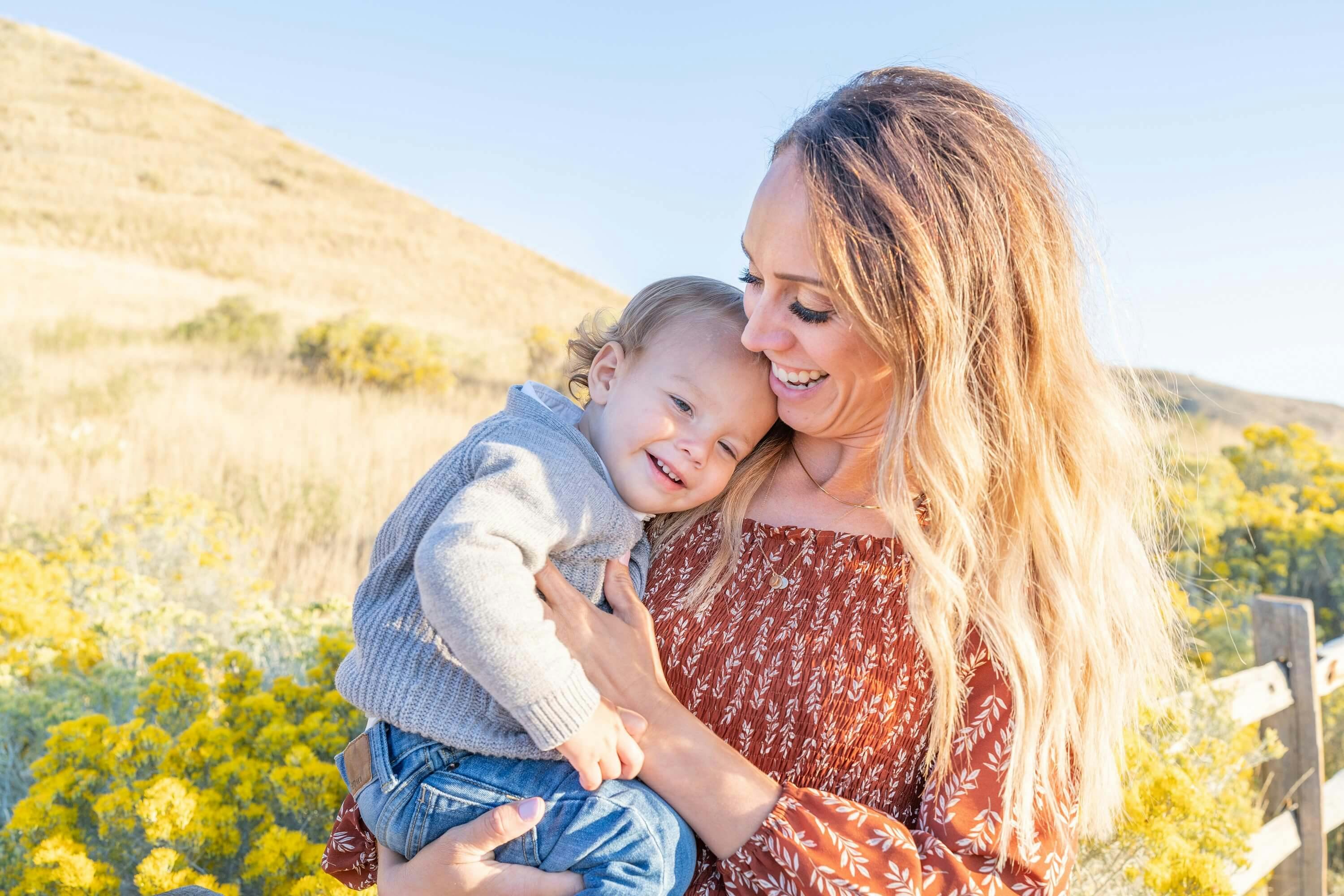 smiling mother holding a baby in a field of flowers