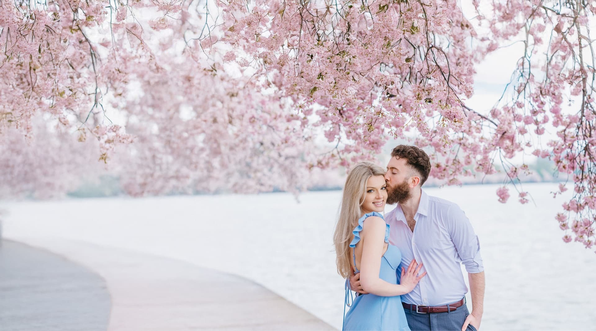 A couple smiles together, surrounded by the beautiful sights of Washington DC & cherry blossoms in a romantic photo session.