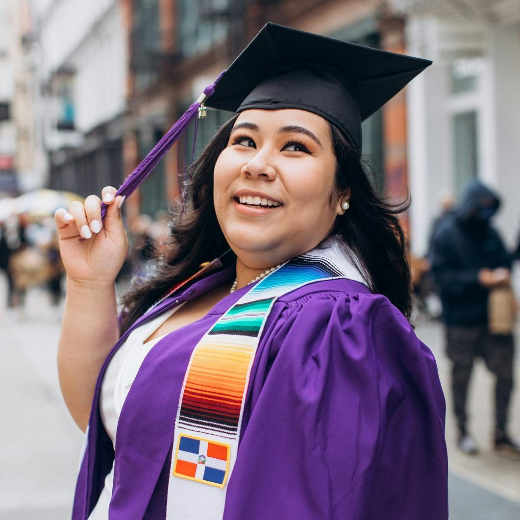 woman in a purple graduation gown on a busy street