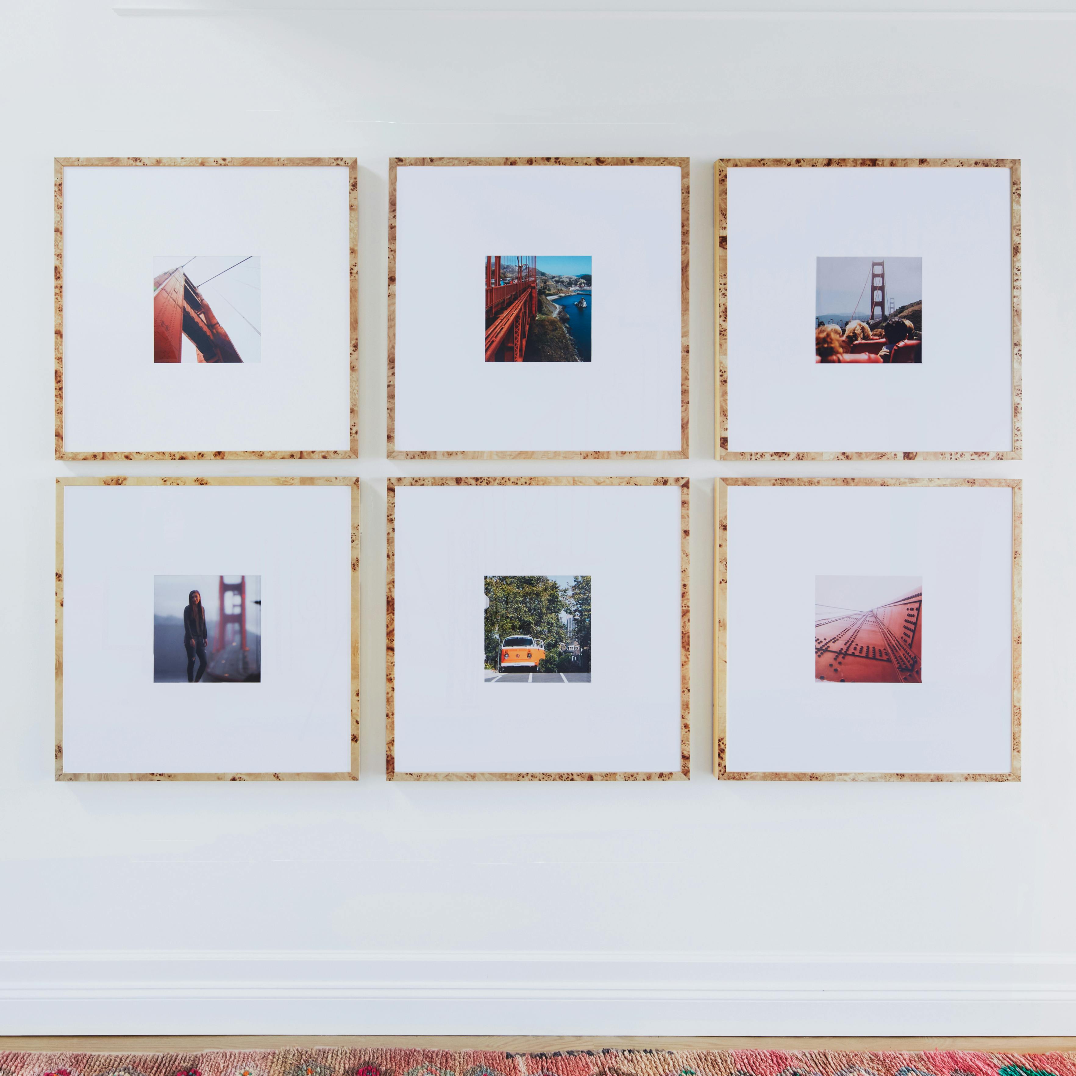 A gallery wall featuring six framed photographs with various urban and architectural themes.