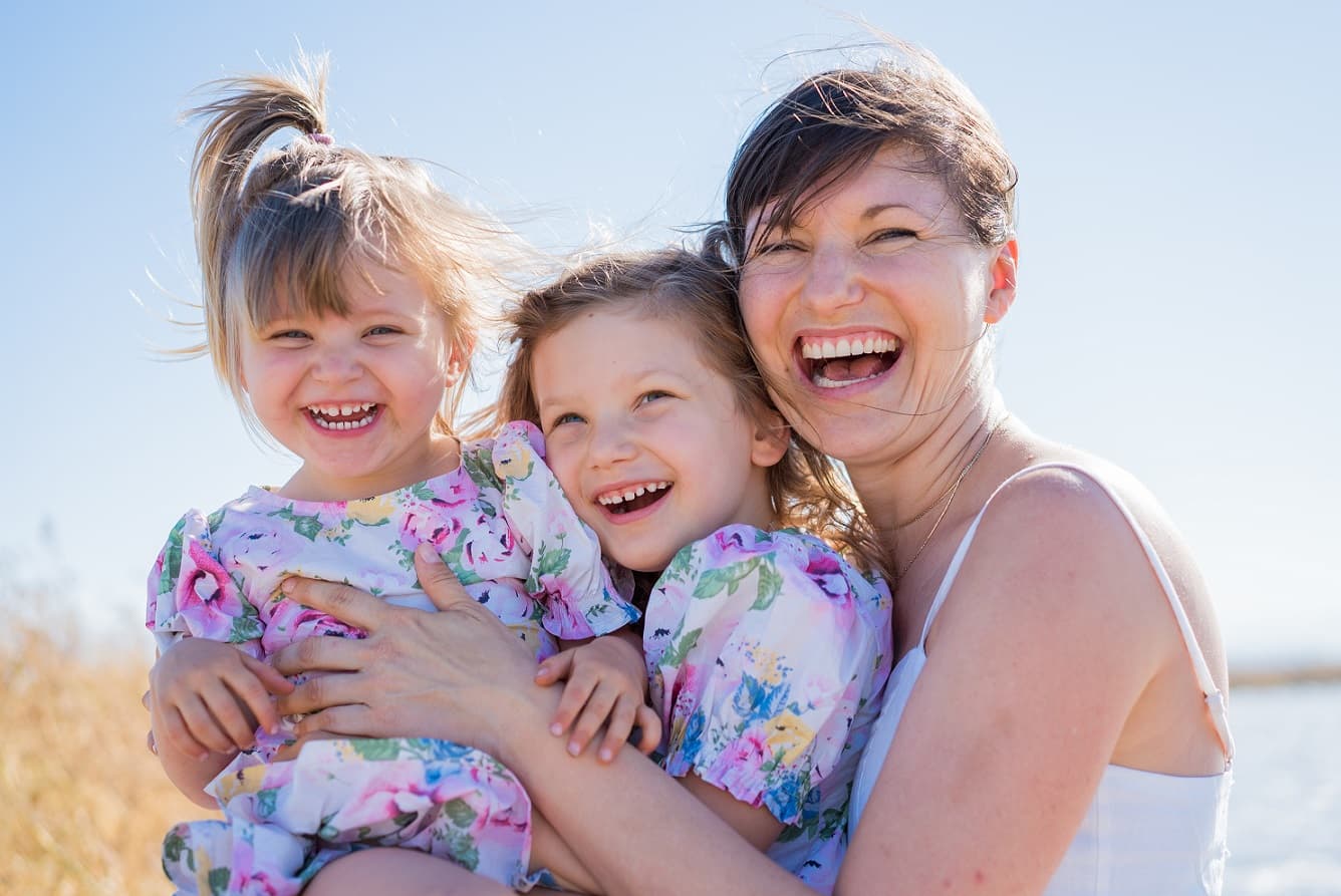 mother and two kids posing for a photoshoot on a beach