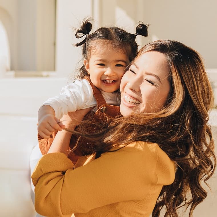 mother holding a baby in front of a fabric background