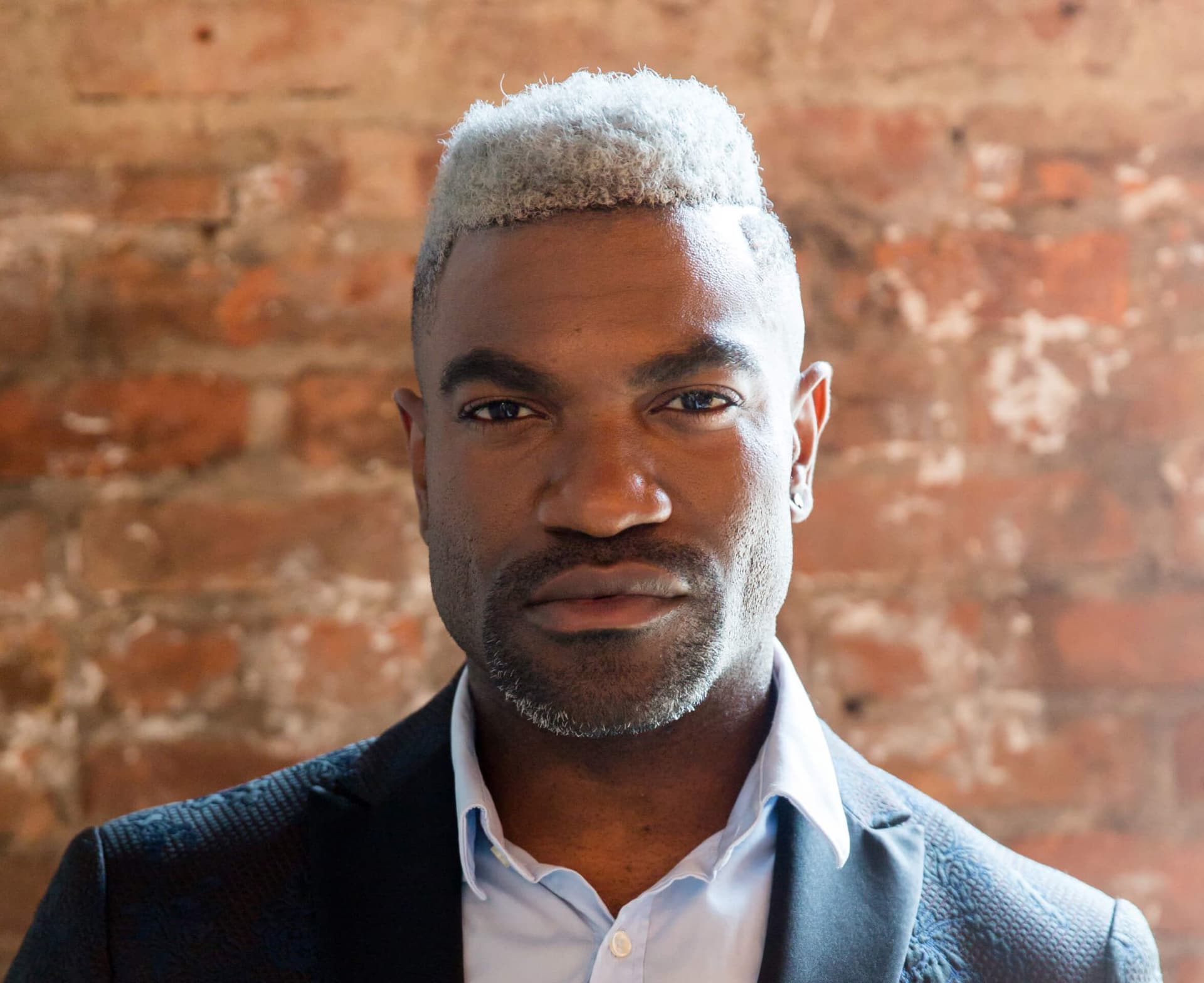 business headshot of a man in a suit in front of a brick wall