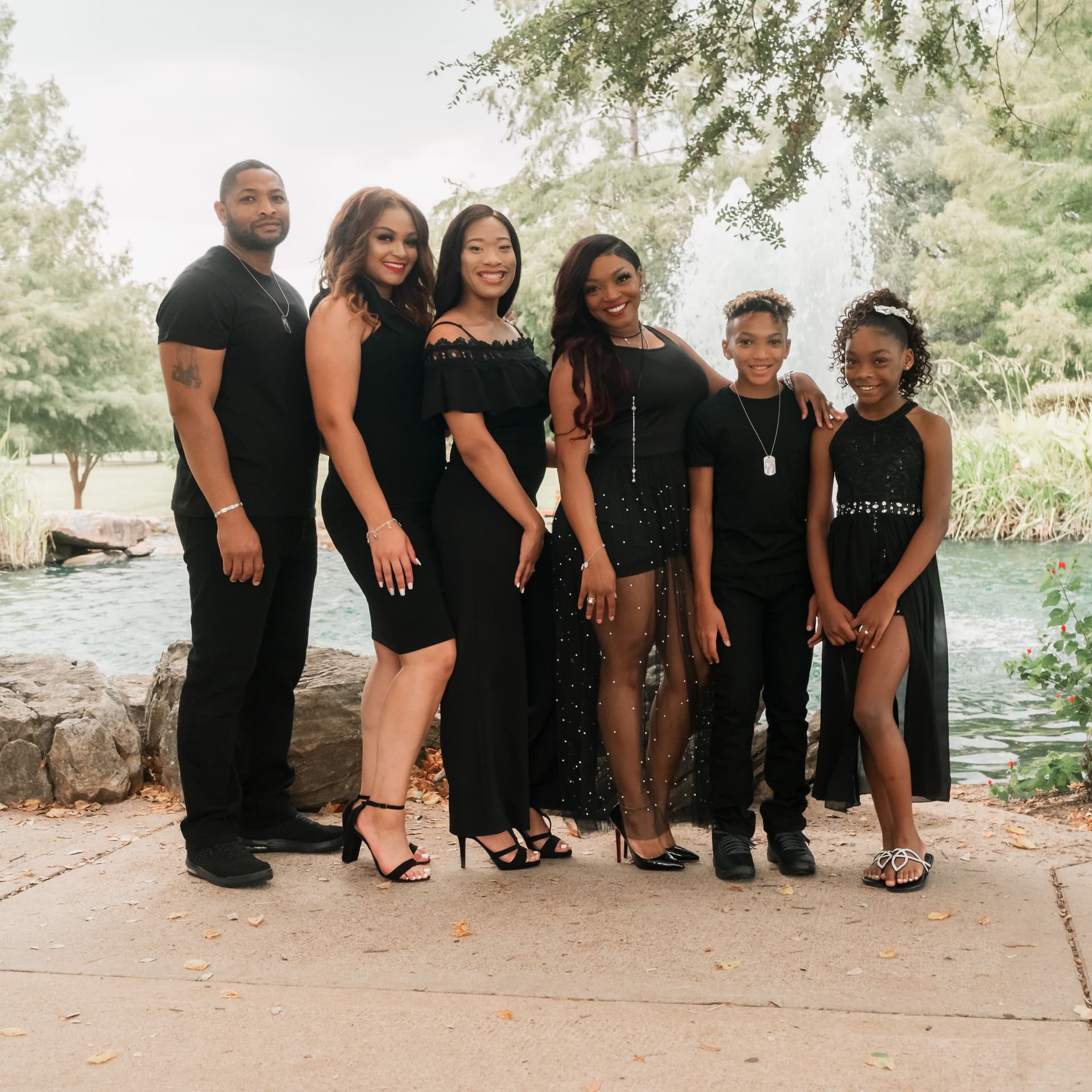 Family in matching outfits pose by a lake for their free outdoor photoshoot