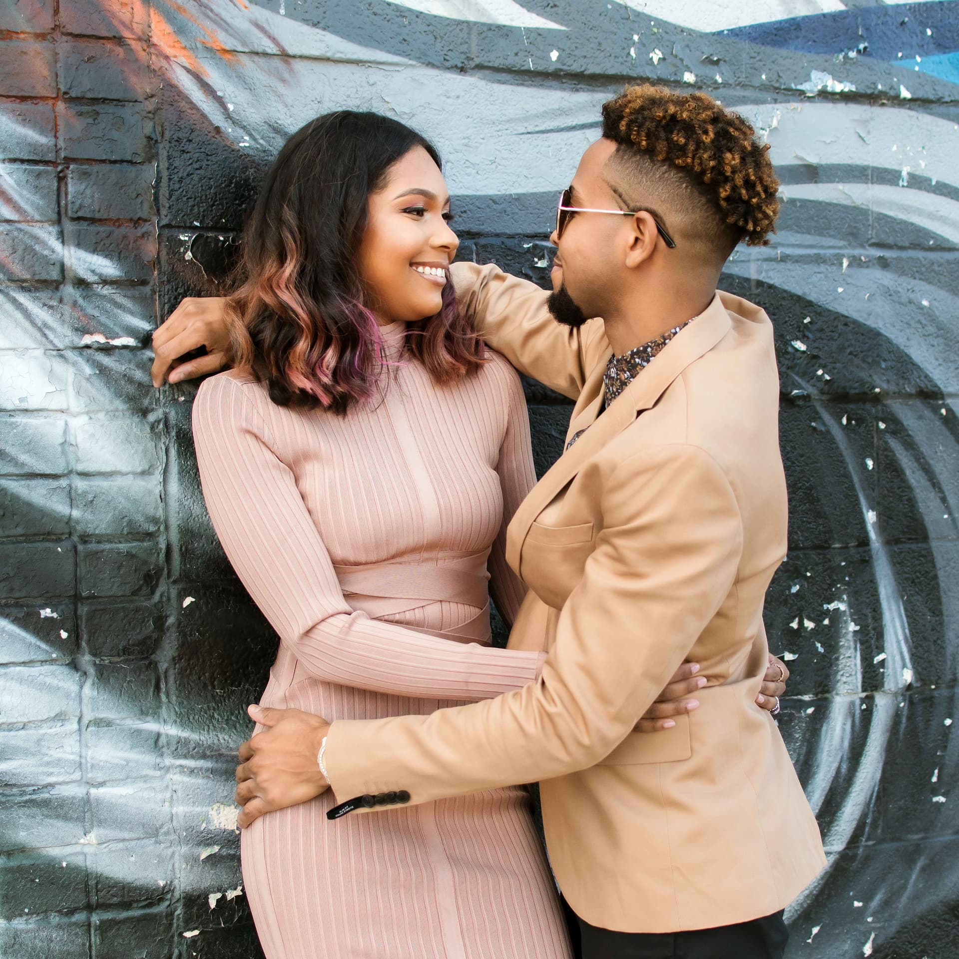 Couple hugs in front of a city mural for their free outdoor engagement photoshoot