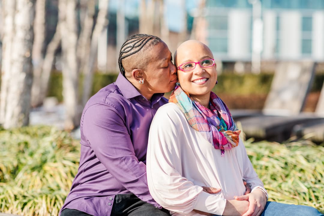 Man kissing woman on the forehead while sitting outdoors.