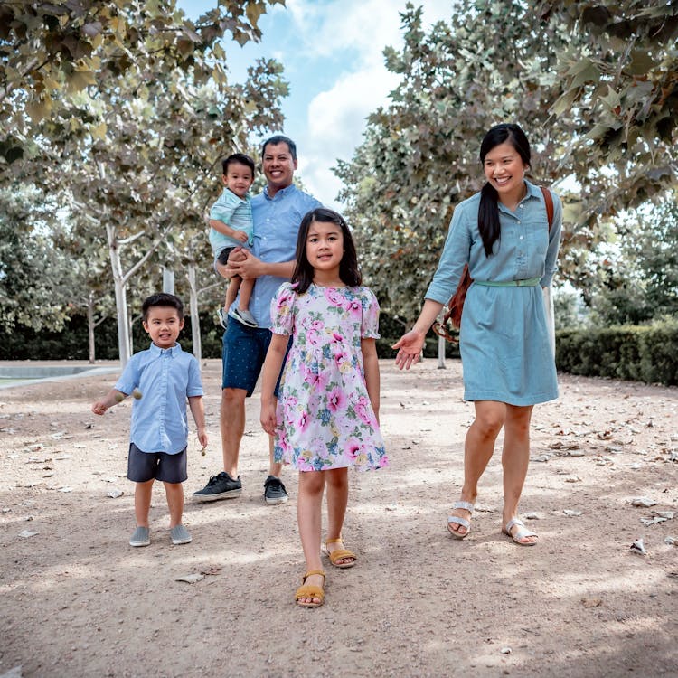 Family in matching blue outfits walk through the park for their free outdoor family photoshoot