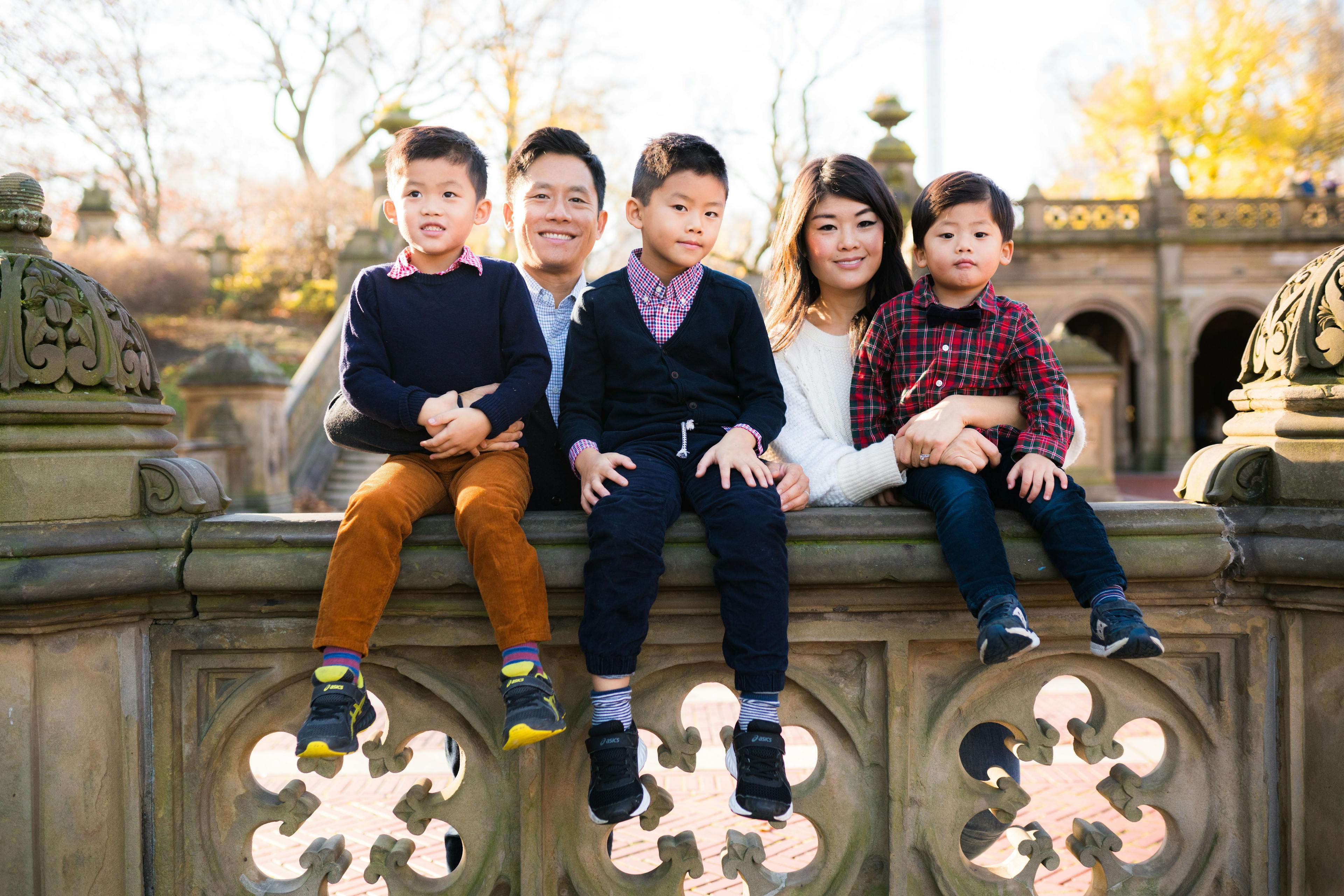 A family of five poses happily on an ornate bridge.
