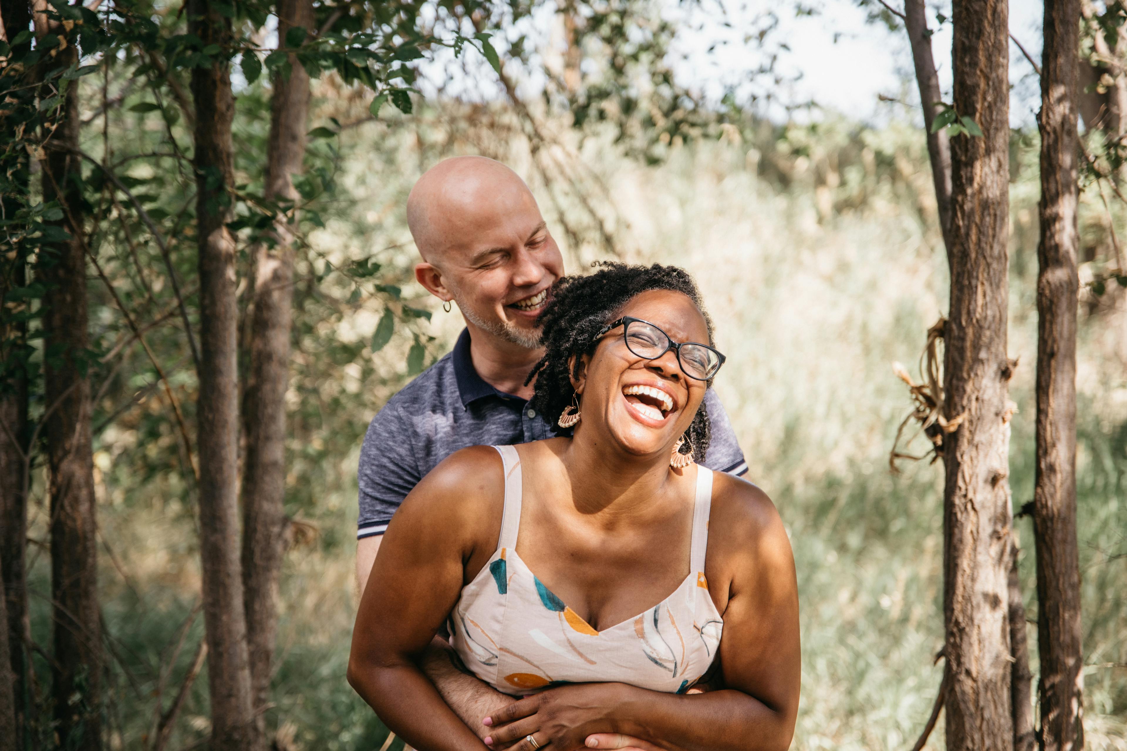 Couple laughing together in a forested area