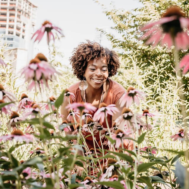 A joyful woman surrounded by pink flowers in a garden