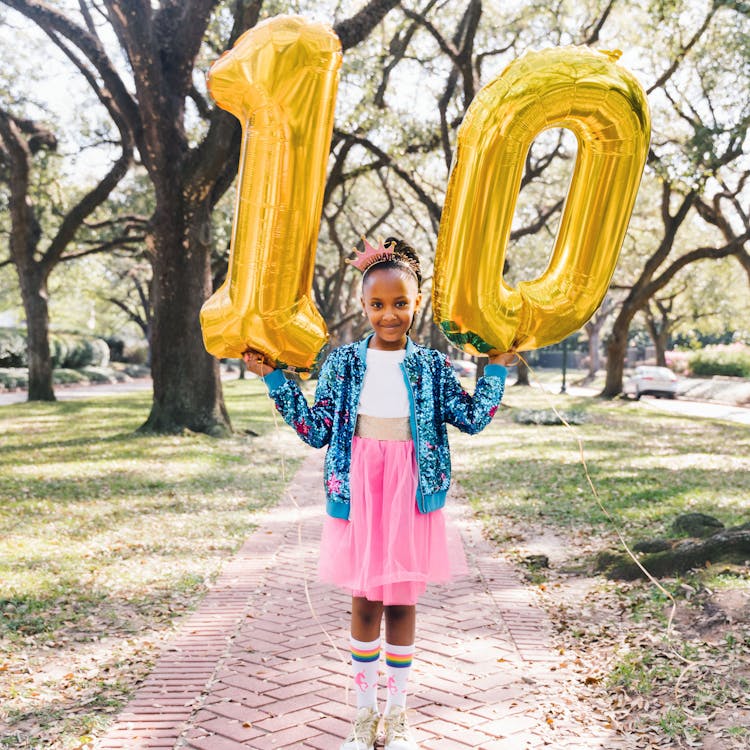 Girl holds number balloons for her free outdoor birthday photoshoot