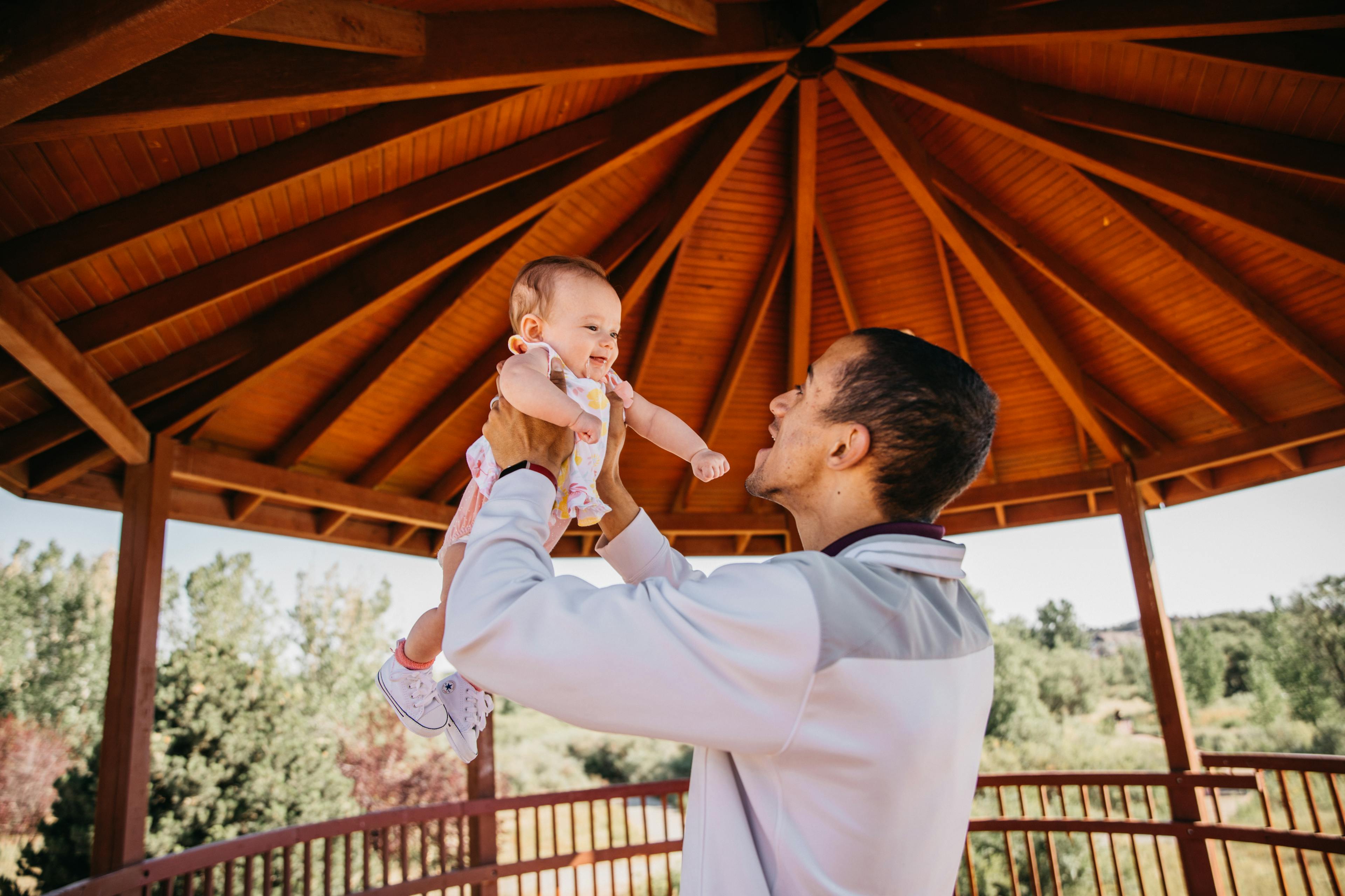 Father lifting up his smiling baby high in a gazebo