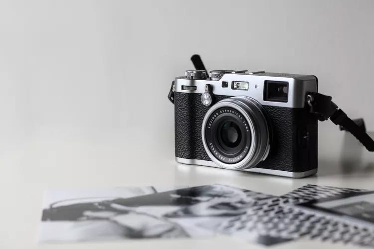 Vintage camera on a white surface with out-of-focus printed photos.