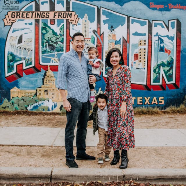 A family standing in front of a colorful mural with 'Greetings from Austin Texas' written on it.