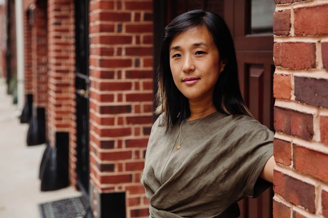 A woman standing by a brick building in an urban area