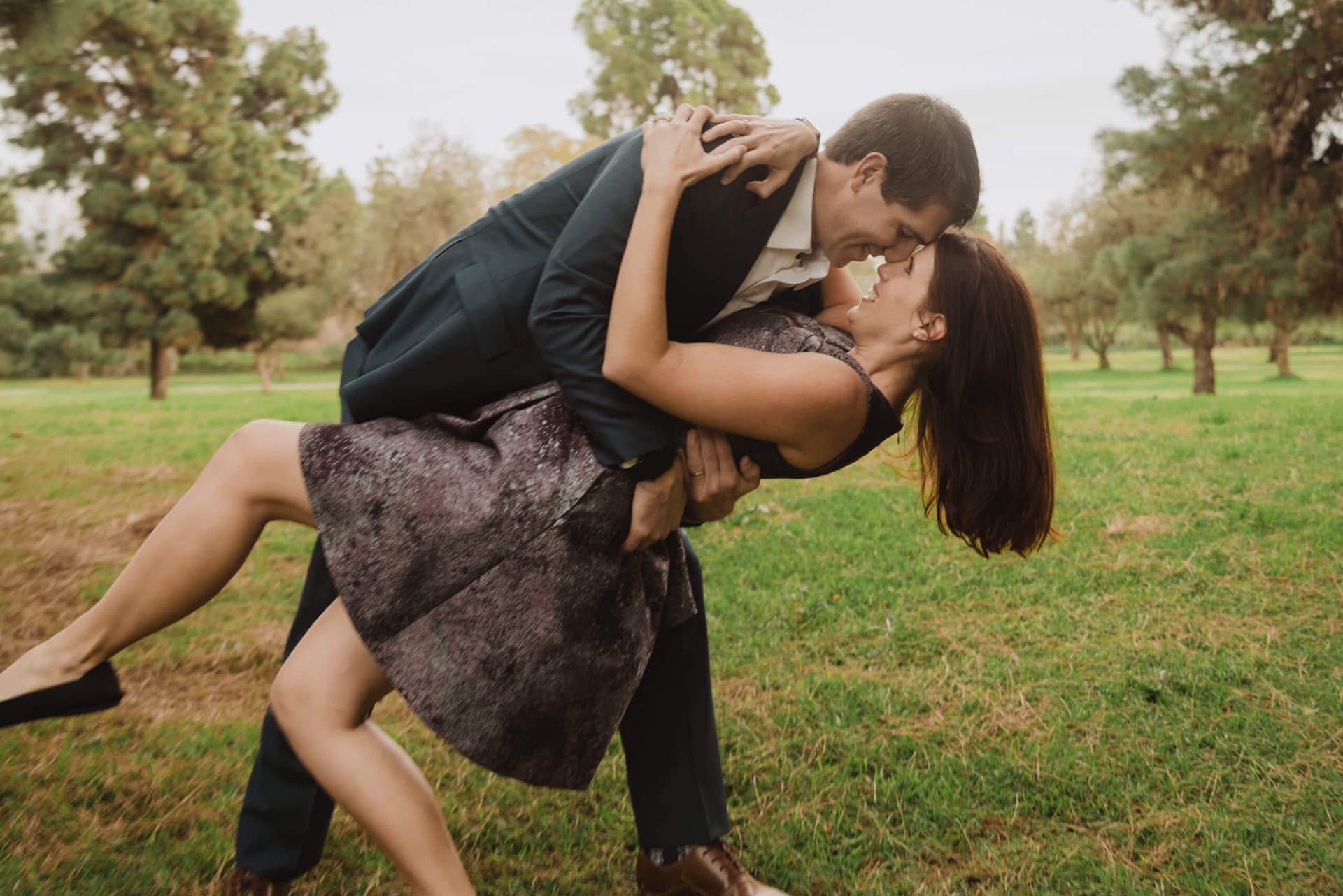 Man dipping a woman in a romantic dance move on a grass field