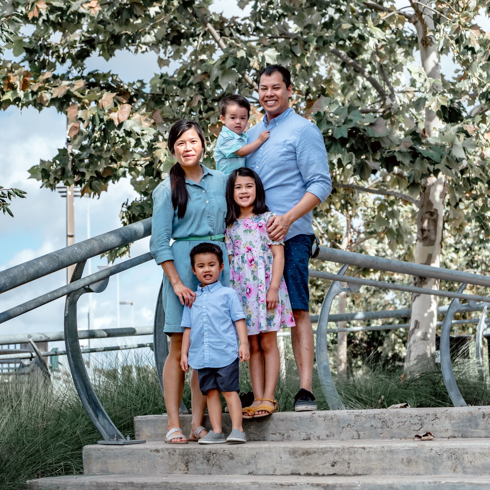 Family in matching blue outfits walk through the park for their free outdoor family photoshoot