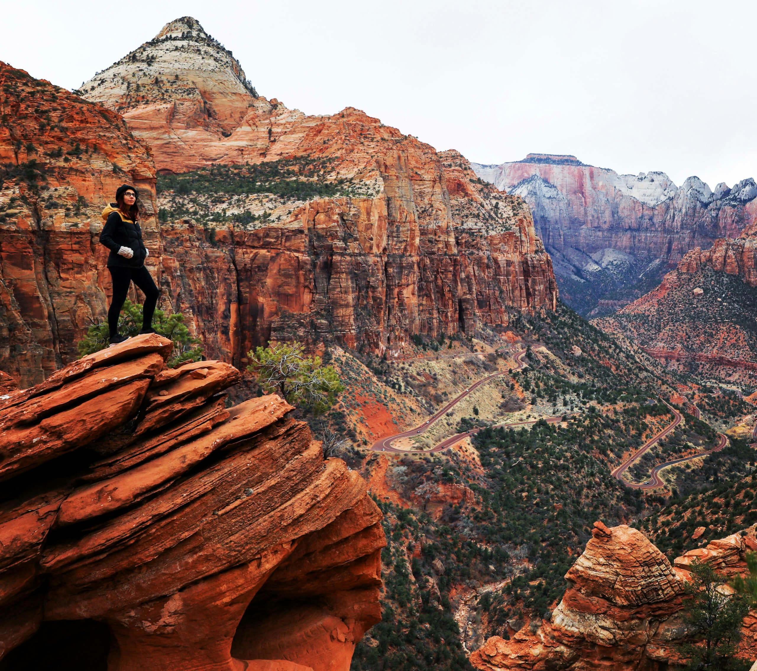 Hiker standing on a red rock formation with panoramic views of mountains