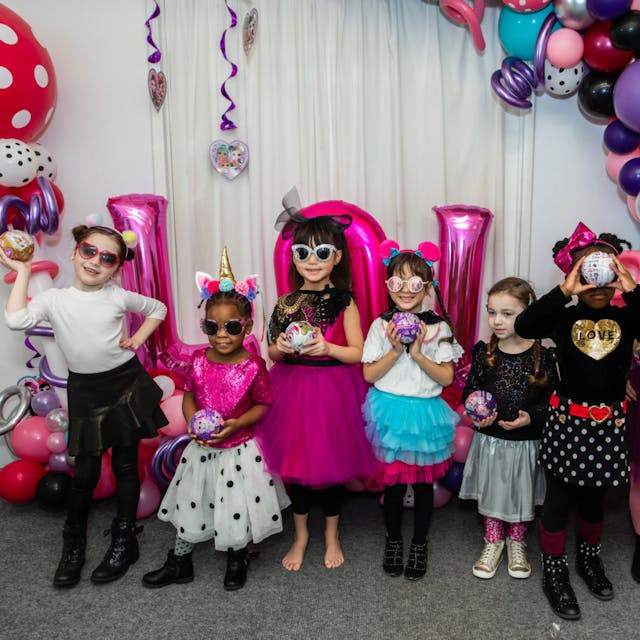 Group of children in costumes posing with masks and props at a birthday party