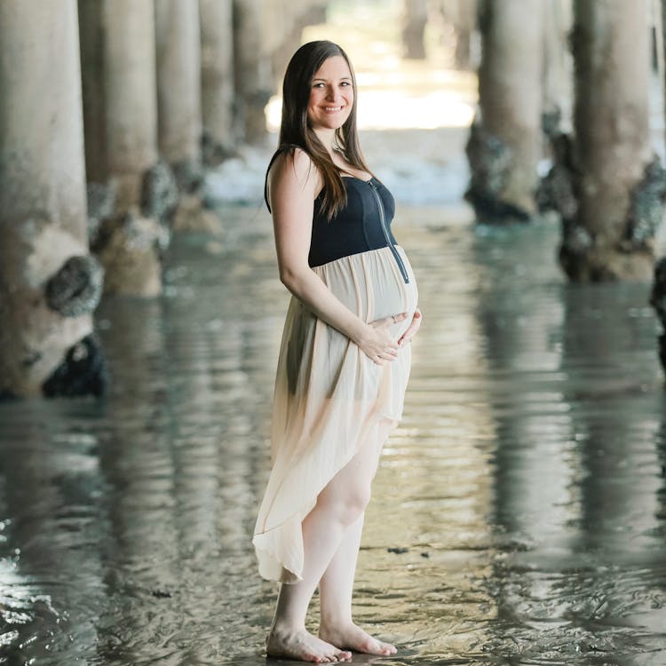 Pregnant woman poses on the beach for her free beach maternity photoshoot
